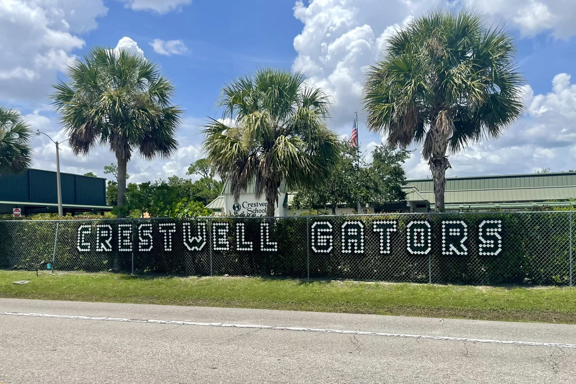 Front of the campus at Crestwell School in Fort Myers, with palm trees and a hedge sign that reads Crestwell Gators