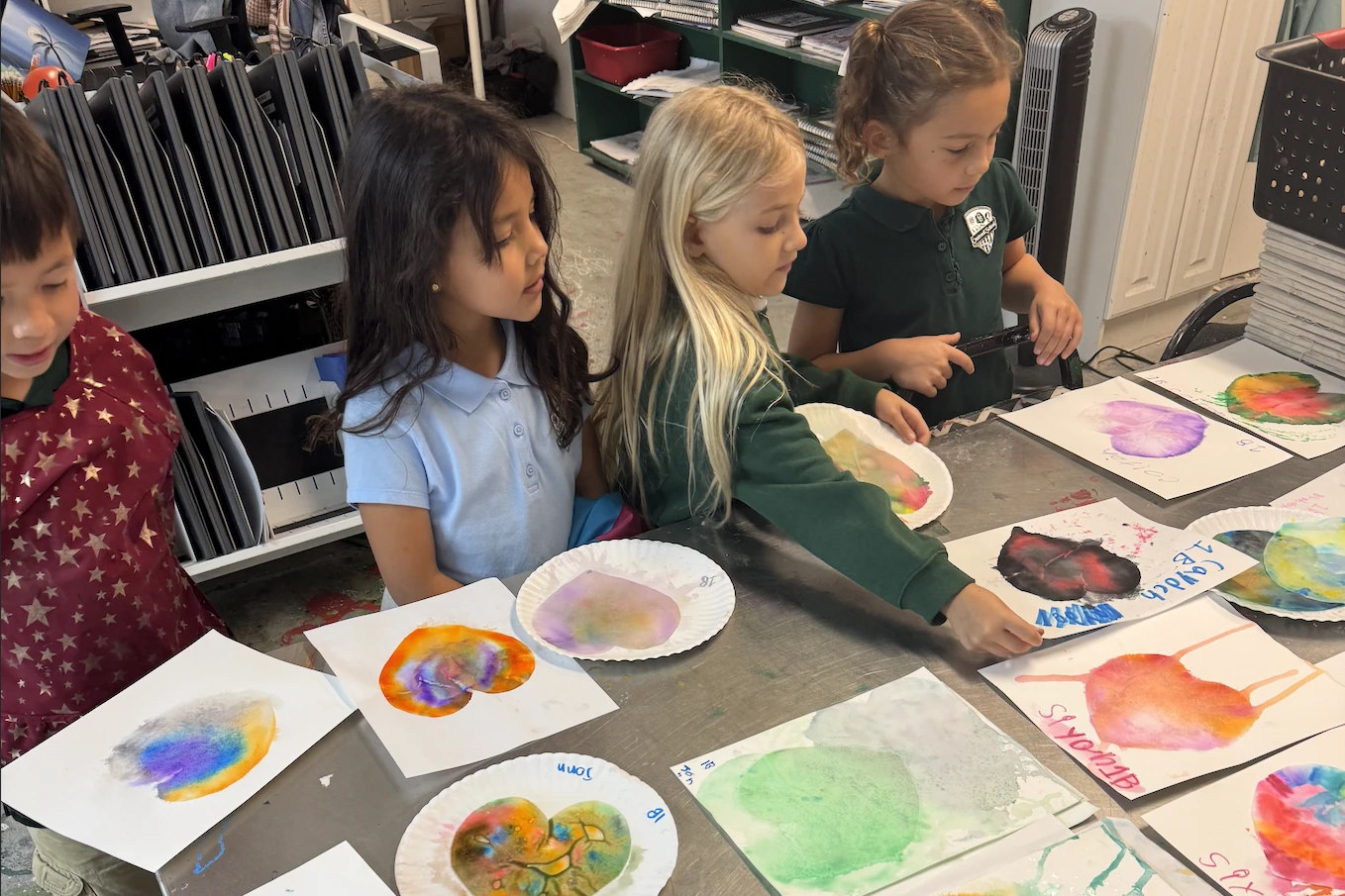 Young Crestwell School students painting with watercolors at a table in the art room